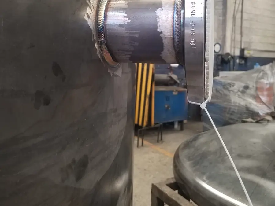 Cordón de soldadura TIG en la unión de una boquilla con su brida de acero, sobre un recipiente en el taller